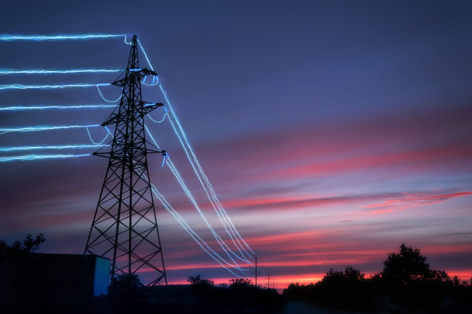 Electric,Transmission,Towers,With,Glowing,Wires,Against,The,Sunset,Sky